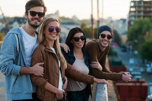 Young and beautiful. Group of young people standing close to each other on the bridge and looking at camera with smiles photo