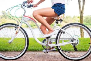 Park ride. Close-up side view of young woman riding bicycle in park photo