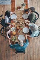 Top view of multi-generation family holding hands and praying while having dinner together photo