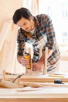 esto se va a ver increíble. joven carpintero concentrado lijando una silla de madera en su taller foto