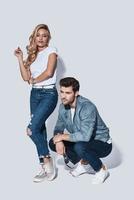 They belong together. Full length of beautiful young couple bonding while standing against grey background photo