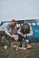 Looks delicious.  Beautiful young couple roasting marshmallows over a campfire while enjoying their road travel photo