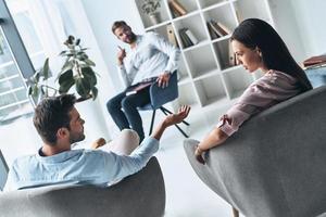 tratando de entender ambos lados. joven pareja casada hablando mientras se sienta en la sesión de terapia con el psicólogo foto