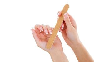 Nail care. Cropped image of woman polishing nails while isolated on white photo