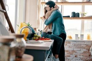 Love is more than just a game for two. Beautiful young couple cooking dinner and drinking wine while standing in the kitchen at home photo