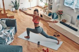 vista superior de una mujer joven de buen aspecto en ropa deportiva haciendo ejercicio mientras pasa tiempo en casa foto