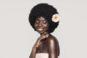 Portrait of beautiful young African woman touching shoulder and smiling photo