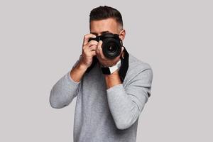 Nice shot. Good looking young man photographing you while standing against grey background photo