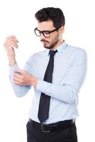 Everything should be perfect. Confident young man in shirt and tie adjusting his sleeve while standing against white background photo