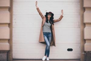 Feeling carefree. Full length of beautiful young woman in sunglasses looking away with smile and keeping arms outstretched while standing outdoors photo