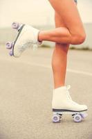 Ready to roller skating. Close-up of young woman in roller skates lifting her leg up while standing outdoors photo