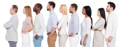 Waiting in a row. Side view of confident diverse group of people in smart casual wear looking away while standing in a row and against white background photo