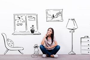 soñando con casa nueva. una joven pensativa mirando el boceto en la pared mientras se sienta en el suelo foto