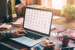 Working at home. Close-up image of man working on laptop with copy space while sitting at the rustic wooden table photo