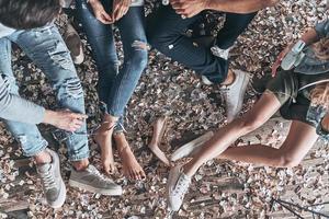 Party is over. Close up top view of young people resting while sitting on the floor with confetti around photo