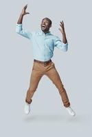 Playful young African man shouting while hovering against grey background photo