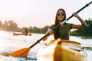 Buen día en kayak. hermosa joven mujer sonriente kayak en el río foto