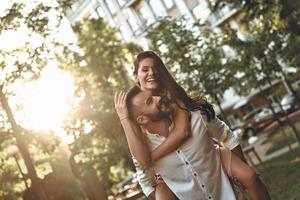 Totally in love. Handsome young man giving his girlfriend a piggyback ride while spending time together photo