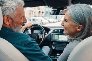 vista trasera de una pareja mayor activa que disfruta de un viaje en auto mientras se sienta en los asientos delanteros del auto foto