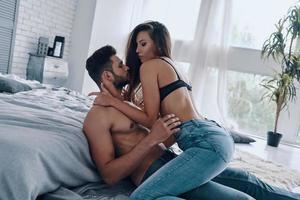 hermosa joven pareja semi-vestida a punto de hacer el amor mientras pasa tiempo en casa foto