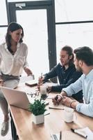 Concentrated at work. Young modern colleagues in smart casual wear working together and smiling while spending time in the office photo