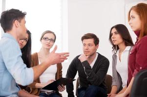 I want to share my problem. Group of people sitting close to each other while man telling something and gesturing photo