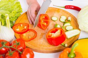 Cutting vegetables. Close-up of woman cutting vegetable on the cutting board photo