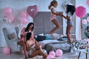 diversión y alegría. cuatro amigas en pijama uniéndose mientras pasan tiempo en el dormitorio foto