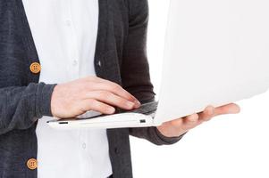 Working on laptop. Close-up of man working on laptop while standing isolated on white photo