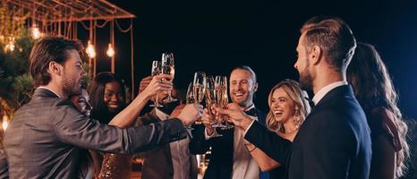 Group of beautiful people in formalwear toasting with champagne and smiling while spending time on luxury party photo