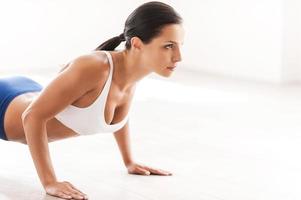 mujer haciendo flexiones. vista lateral de una hermosa joven con ropa deportiva haciendo flexiones foto