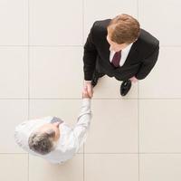 Business partners handshaking. Top view of two business men shaking hands photo