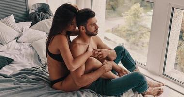 alejarse de todo. vista superior de una hermosa pareja joven semi-vestida abrazándose mientras pasa tiempo en el dormitorio foto