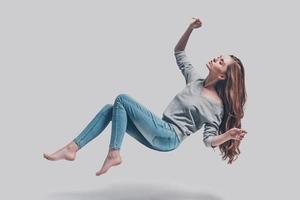 Hovering beauty. Full length studio shot of attractive young woman hovering in air and keeping eyes closed photo