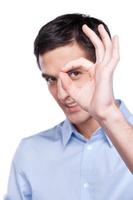 Everything is OK. Portrait of handsome young man in blue shirt showing OK sign with fingers and smiling while standing isolated on white photo