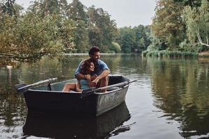 Feeling happy together. Beautiful young couple embracing and smiling while enjoying romantic date on the lake photo