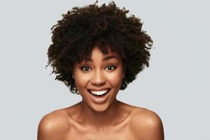 Impossible to resist her. Attractive young African woman looking at camera and smiling while standing against grey background photo