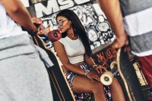 Skater girl. Young attractive woman smiling while spending time with her skate friends outdoors photo