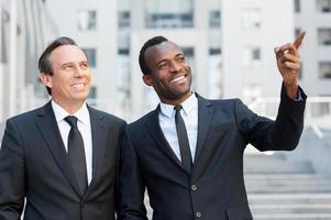 Showing the opportunities. Two cheerful business men talking and gesturing while standing outdoors photo