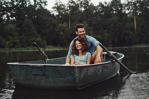 Simple joy of loving. Beautiful young couple embracing and smiling while enjoying romantic date on the lake photo