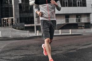 Morning jog. Close up of man in sport clothing running along the street photo