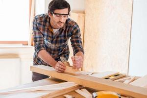 Wood processing. Confident young male carpenter working with wood in his workshop photo