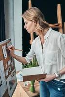 Moments o inspiration. Attractive young woman drawing a sketch while standing in the workshop photo