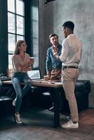 Group of young people in smart casual wear discussing business while working in the office photo