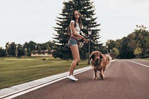 Full length of beautiful young woman playing with her dog and smiling while spending time outdoors photo