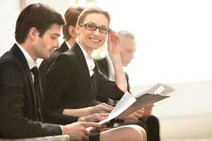 Confident businesswoman. Four people in formalwear waiting in line while beautiful woman looking at camera and smiling photo