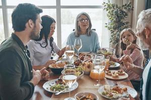 hermosa familia multigeneracional comunicándose y sonriendo mientras cenamos juntos foto