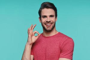 Handsome young man in casual clothing looking at camera and gesturing photo