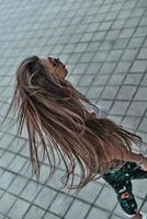 su cabello es su mejor accesorio. vista superior de una hermosa joven con el pelo largo caminando al aire libre foto