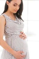 Pregnant woman. Beautiful pregnant woman touching her abdomen and looking at it with smile photo